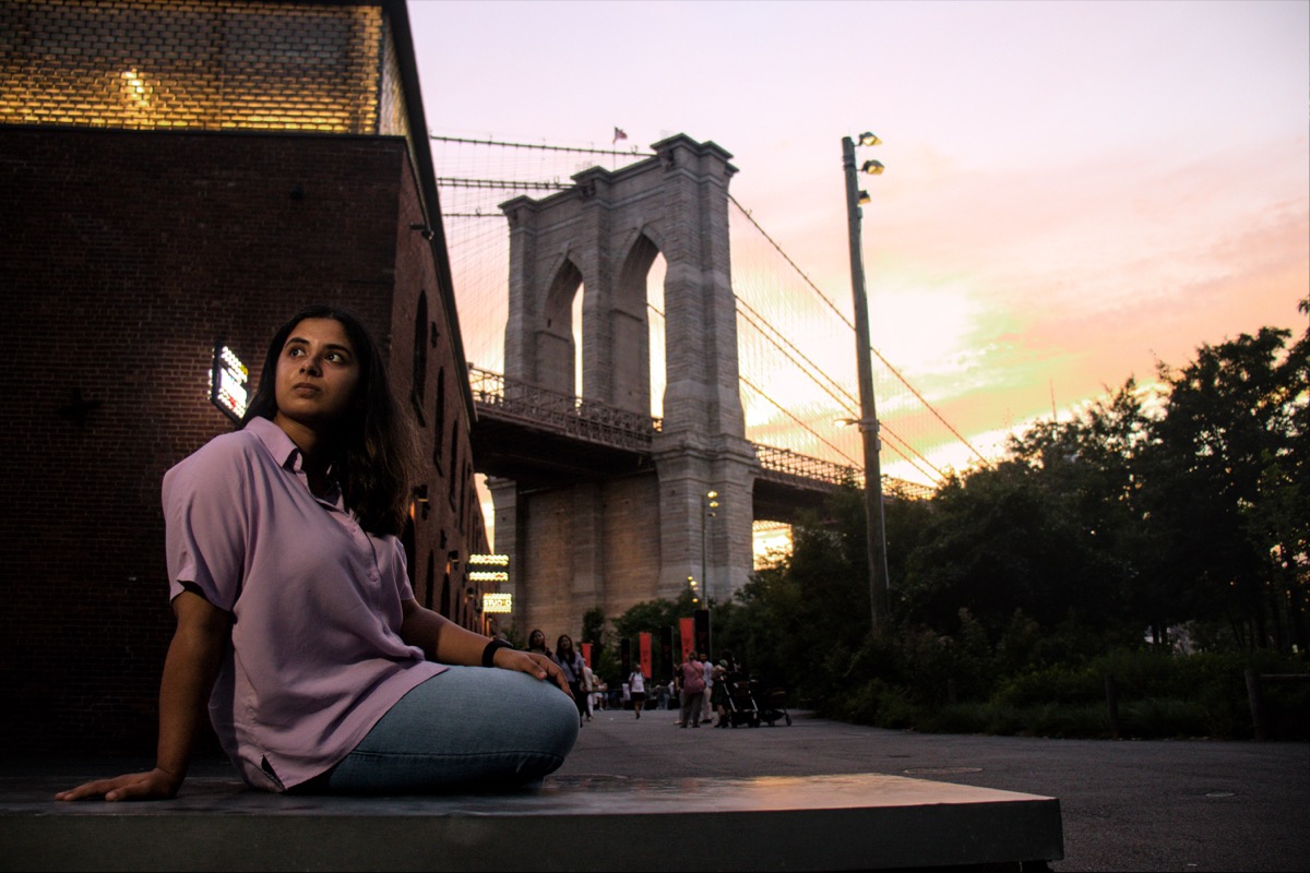 Arya sitting in front of the Brooklyn Bridge